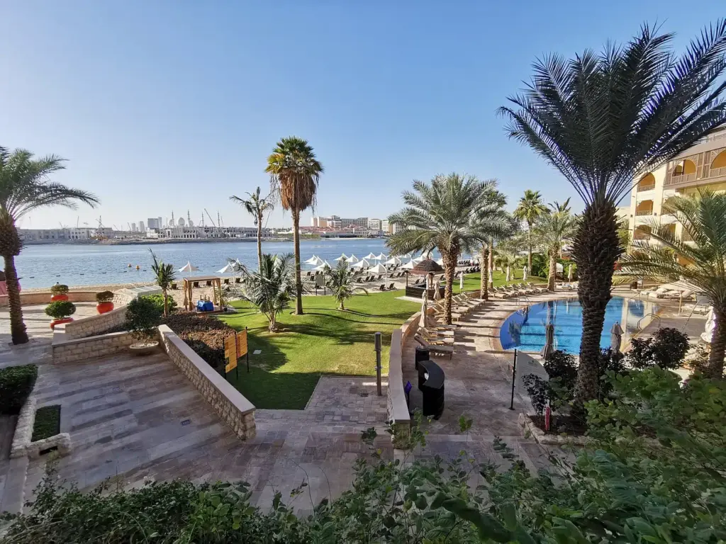 Blick vom Büro von Dubai Strategy auf den Fluß, einem Pool und Palmen.